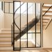Cage d’escalier contemporaine fermée par des panneaux de verre strié et une structure métallique fine, laissant passer largement la lumière naturelle.